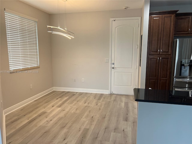 unfurnished dining area with light wood-style floors and baseboards