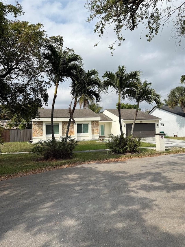 single story home with concrete driveway, fence, and an attached garage