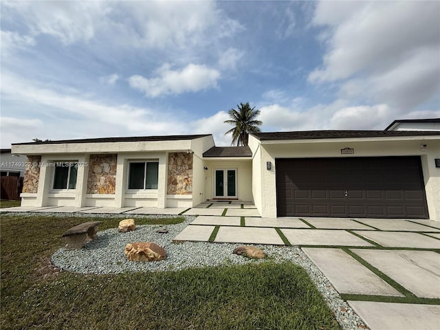 rear view of house with stone siding, driveway, an attached garage, and stucco siding