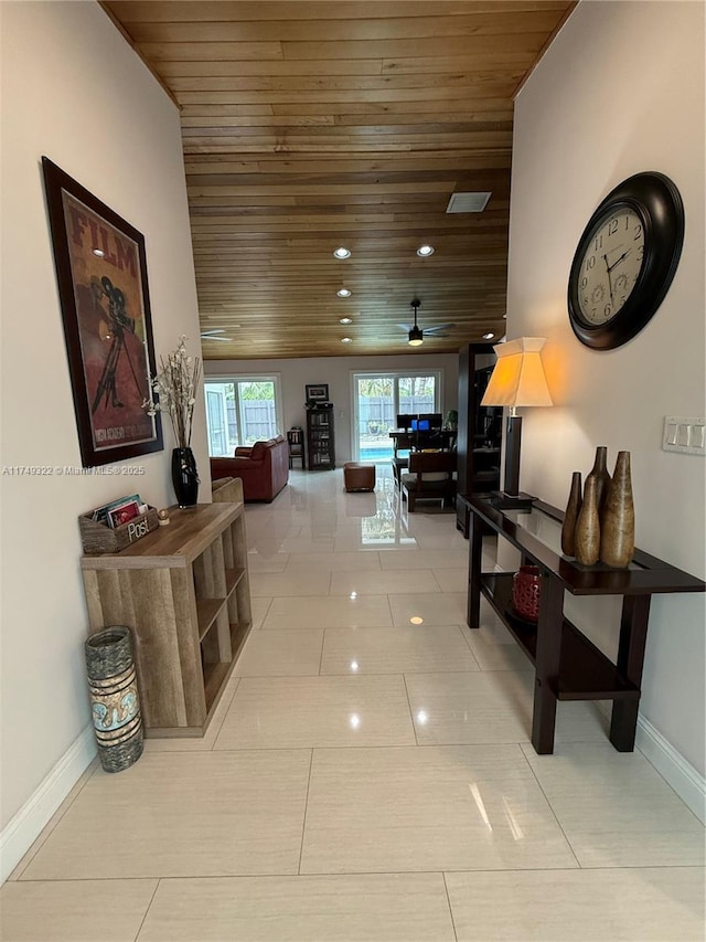 hallway with light tile patterned floors, wood ceiling, and baseboards