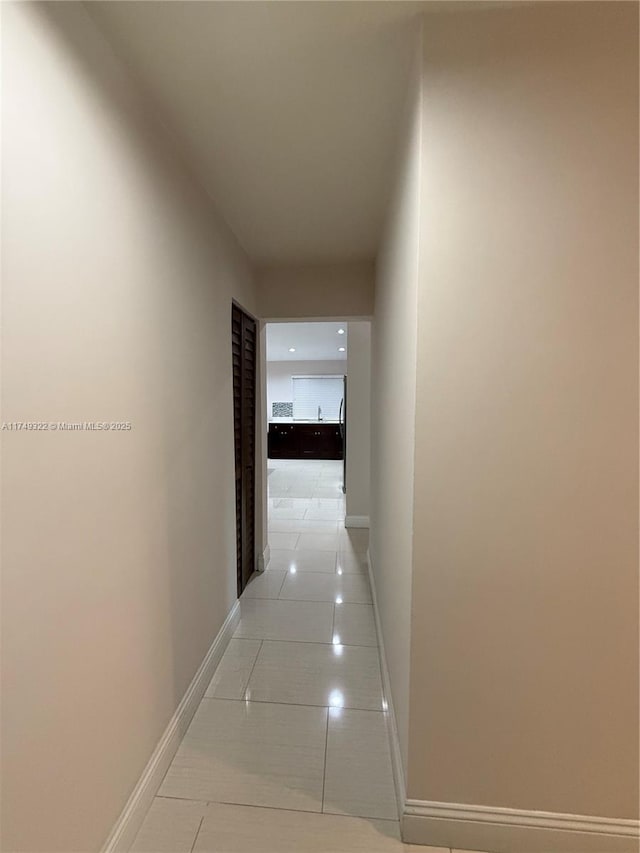 hallway with light tile patterned flooring and baseboards