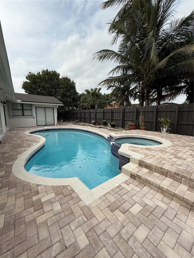 view of pool with a pool with connected hot tub, a fenced backyard, and a patio