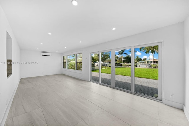 unfurnished living room with baseboards, an AC wall unit, and recessed lighting