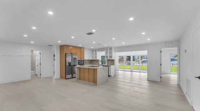 kitchen with stainless steel appliances, visible vents, open floor plan, a center island, and glass insert cabinets