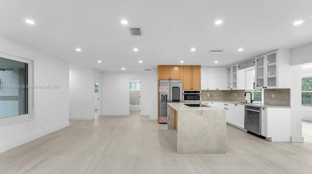 kitchen featuring appliances with stainless steel finishes, white cabinetry, glass insert cabinets, and a center island