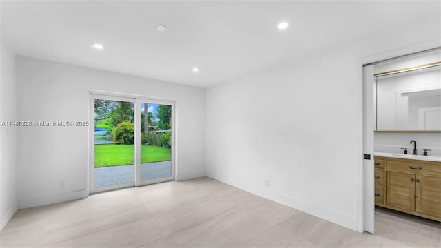 interior space with baseboards, a sink, and recessed lighting