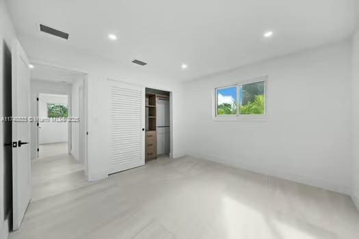 unfurnished bedroom featuring concrete floors, a closet, visible vents, and recessed lighting