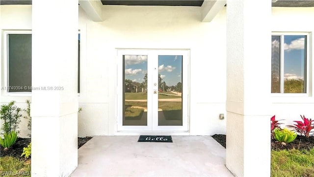 view of exterior entry with stucco siding and french doors