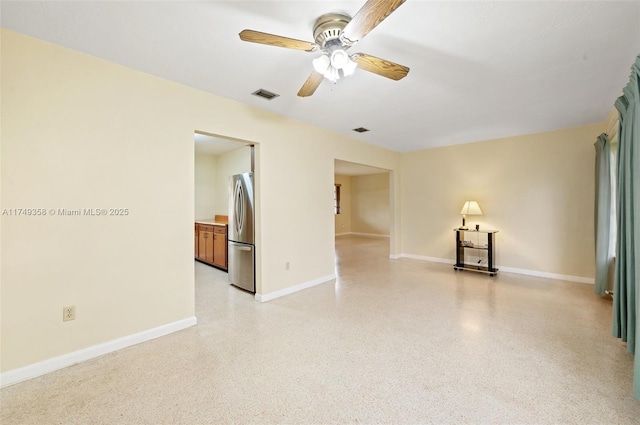 unfurnished room featuring ceiling fan, baseboards, visible vents, and light speckled floor