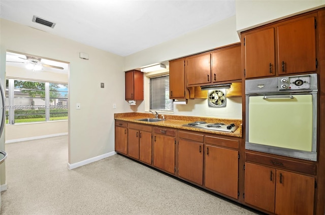 kitchen featuring visible vents, brown cabinets, oven, white cooktop, and a sink