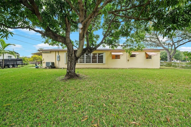 rear view of property with a yard, central AC unit, and stucco siding