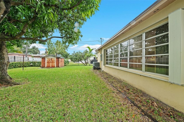 view of yard with central AC, a shed, an outdoor structure, and fence