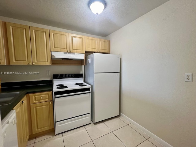 kitchen with light tile patterned floors, under cabinet range hood, white appliances, a sink, and dark countertops