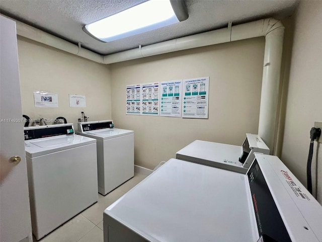 common laundry area featuring light tile patterned floors, washer and clothes dryer, and a textured ceiling