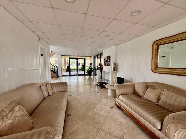 living area with a paneled ceiling, light tile patterned flooring, stairway, and expansive windows