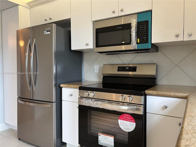 kitchen featuring light tile patterned floors, appliances with stainless steel finishes, white cabinetry, and tasteful backsplash