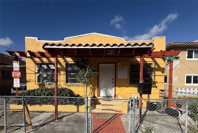 view of front facade featuring a fenced front yard, a tiled roof, and stucco siding