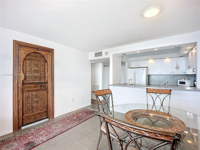 dining area featuring light tile patterned floors, visible vents, and baseboards