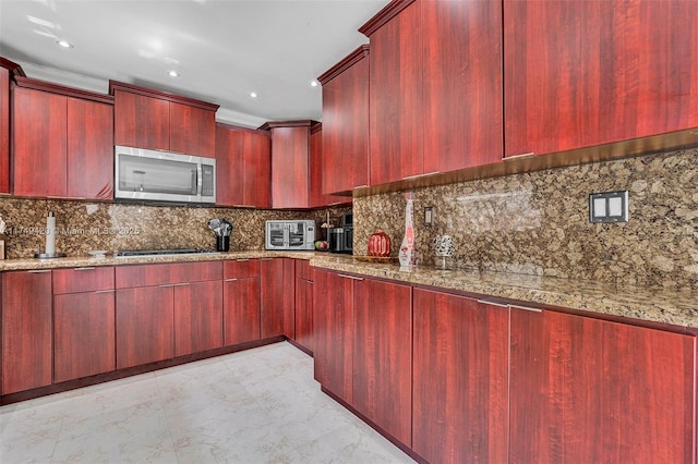 kitchen featuring light stone countertops, dark brown cabinets, ornamental molding, decorative backsplash, and stainless steel microwave