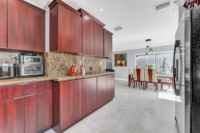 kitchen featuring reddish brown cabinets, marble finish floor, visible vents, and freestanding refrigerator