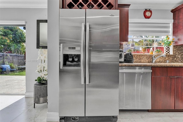 kitchen featuring reddish brown cabinets, ornamental molding, dark stone countertops, marble finish floor, and stainless steel appliances