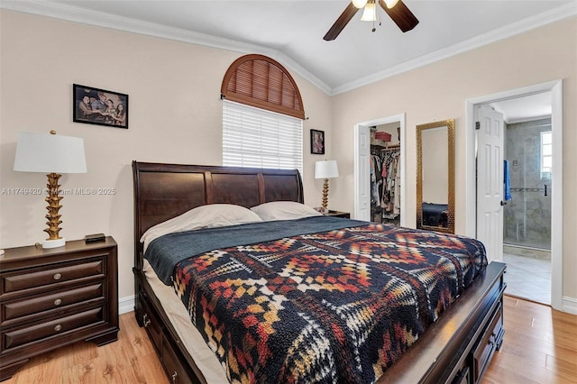 bedroom with crown molding, a spacious closet, vaulted ceiling, and light wood-style floors