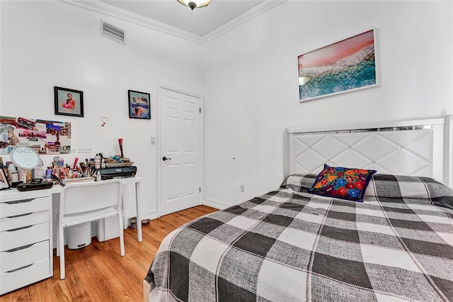 bedroom with visible vents, crown molding, baseboards, and wood finished floors