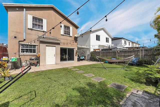 rear view of property featuring a patio, a yard, fence, and stucco siding