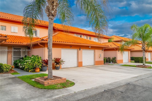 view of front of home with a garage, a tiled roof, driveway, and stucco siding