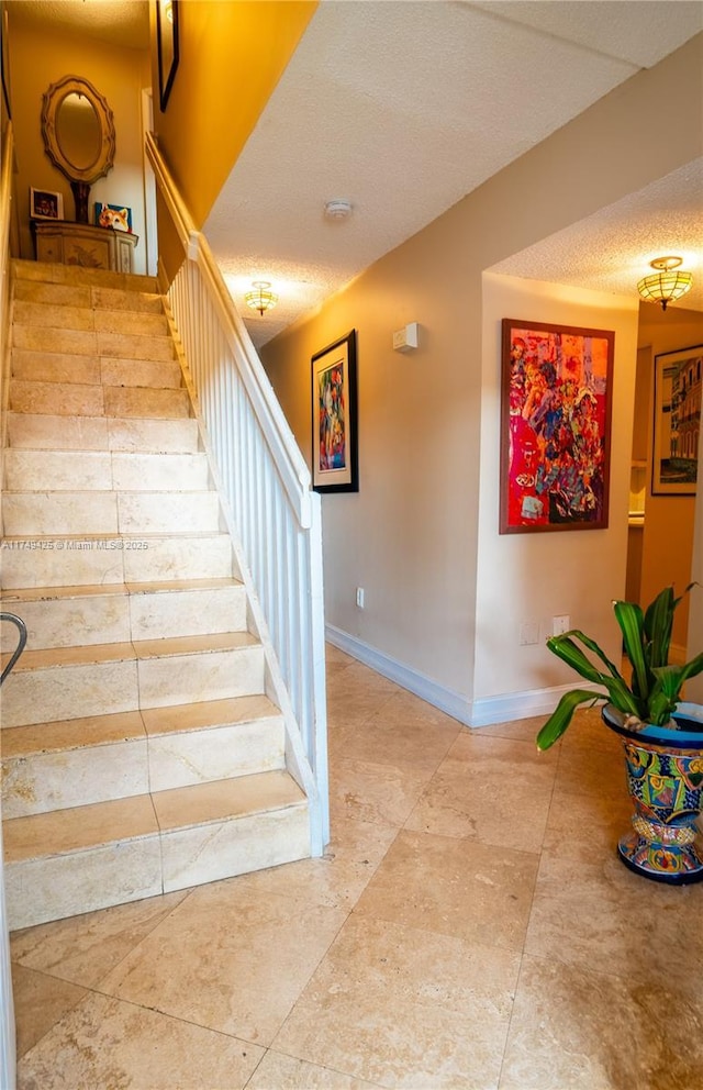 staircase with a textured ceiling and baseboards