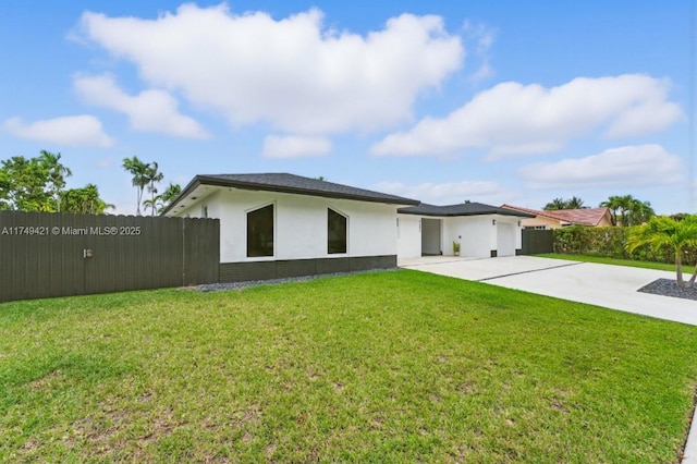 view of front of home featuring an attached garage, fence private yard, driveway, stucco siding, and a front yard