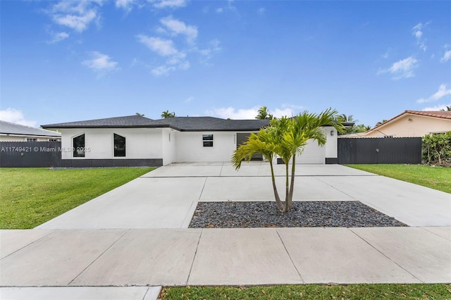 view of front of home with an attached garage, fence, driveway, stucco siding, and a front lawn