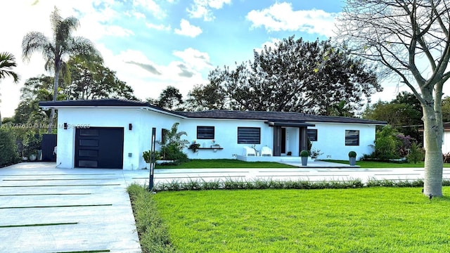 view of front facade with a garage, driveway, a front yard, and stucco siding