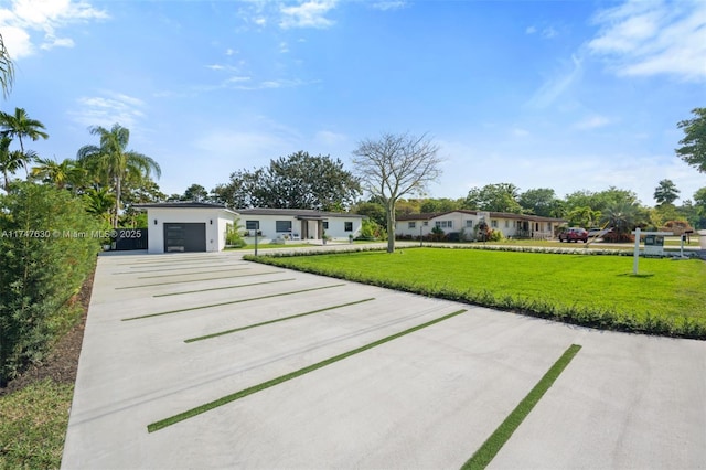 view of front of home with an attached garage, concrete driveway, and a front lawn