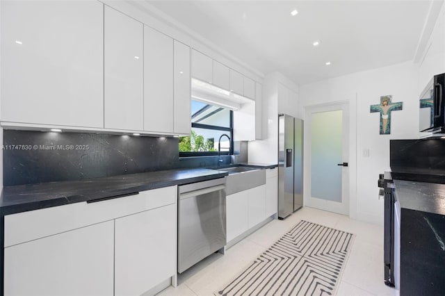 kitchen with dark countertops, tasteful backsplash, stainless steel appliances, white cabinetry, and modern cabinets