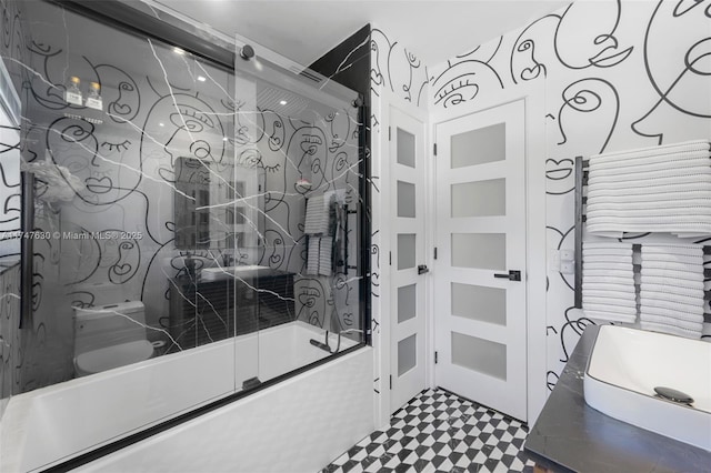 bathroom featuring vanity, toilet, and shower / bath combination with glass door