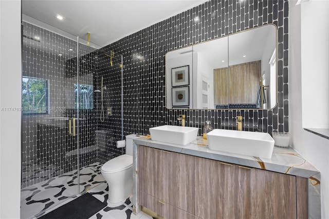 bathroom featuring tile walls, toilet, a stall shower, and a sink