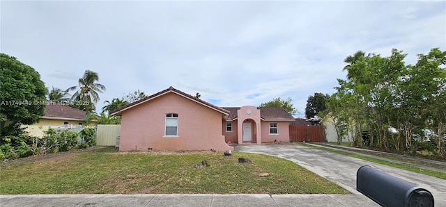 view of front of home with driveway, a front lawn, fence, and stucco siding