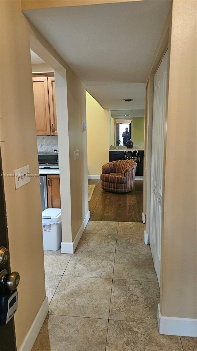 corridor with light tile patterned flooring and baseboards