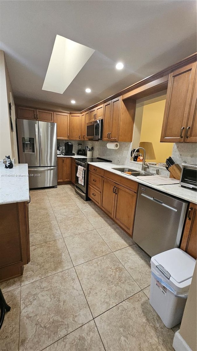 kitchen with tasteful backsplash, light countertops, appliances with stainless steel finishes, light tile patterned flooring, and a sink