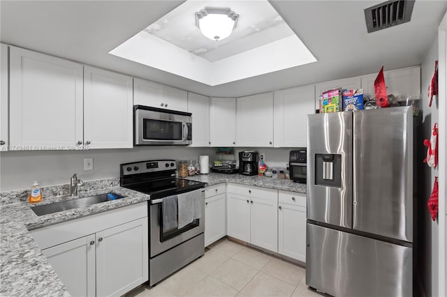 kitchen featuring light tile patterned flooring, stainless steel appliances, a sink, visible vents, and white cabinets