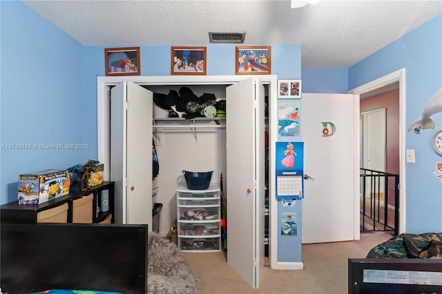 bedroom with a textured ceiling, carpet floors, a closet, and visible vents