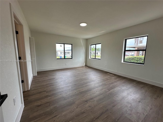 spare room featuring dark wood-style flooring and baseboards