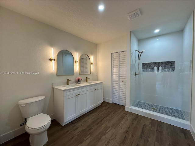 bathroom with a closet, visible vents, toilet, a sink, and wood finished floors