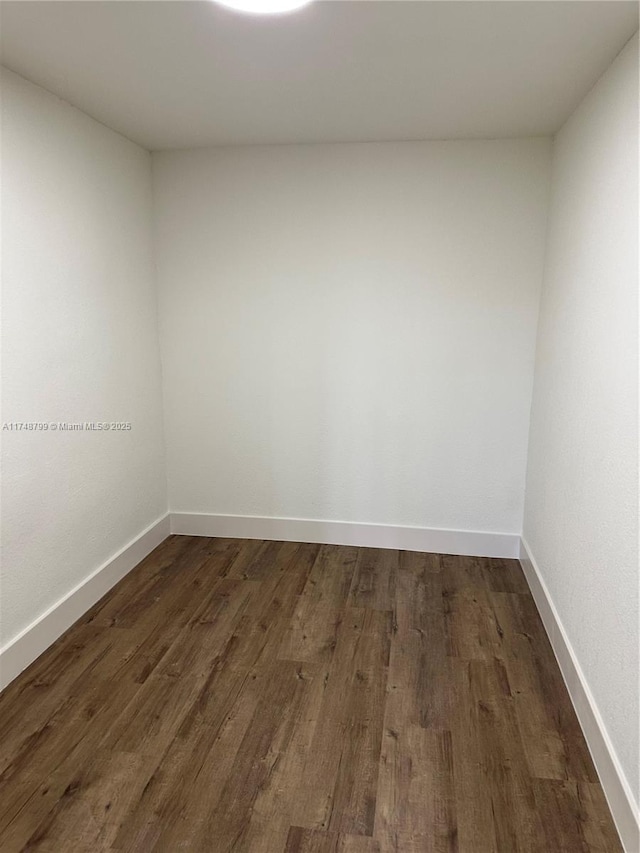 unfurnished room featuring dark wood-style flooring and baseboards