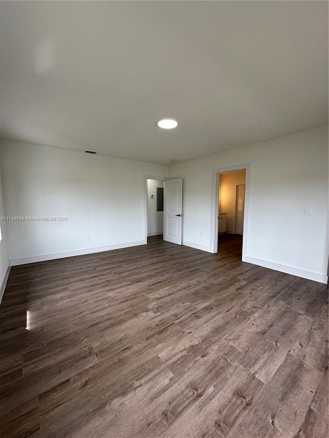 unfurnished room with dark wood-style flooring and baseboards