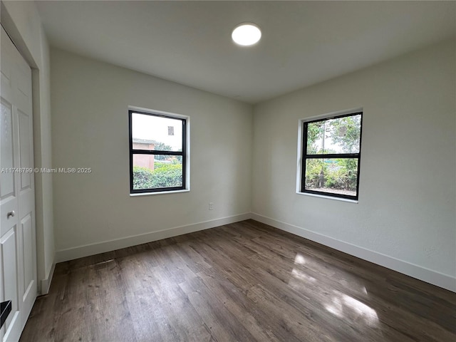 empty room featuring plenty of natural light, wood finished floors, and baseboards