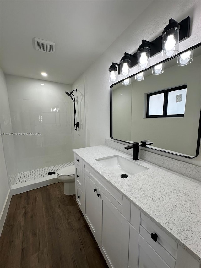 full bath with toilet, wood finished floors, vanity, visible vents, and a shower stall