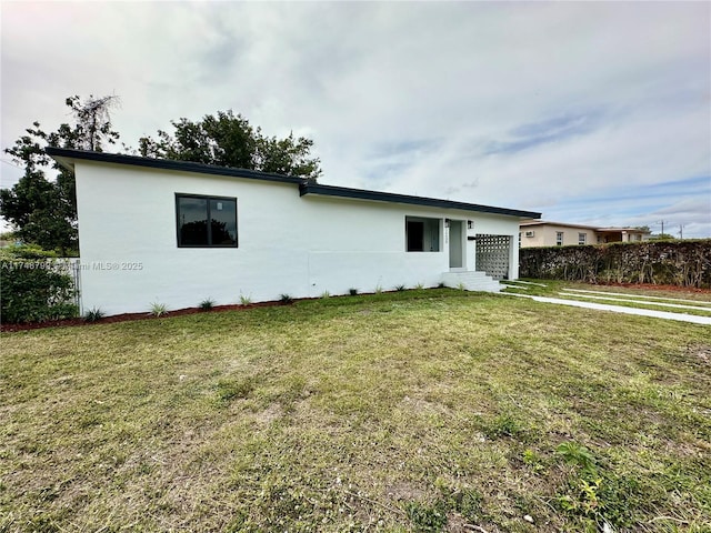 view of front of property featuring fence, a front lawn, and stucco siding