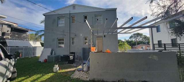 exterior space featuring central air condition unit, fence, a lawn, stucco siding, and a pergola